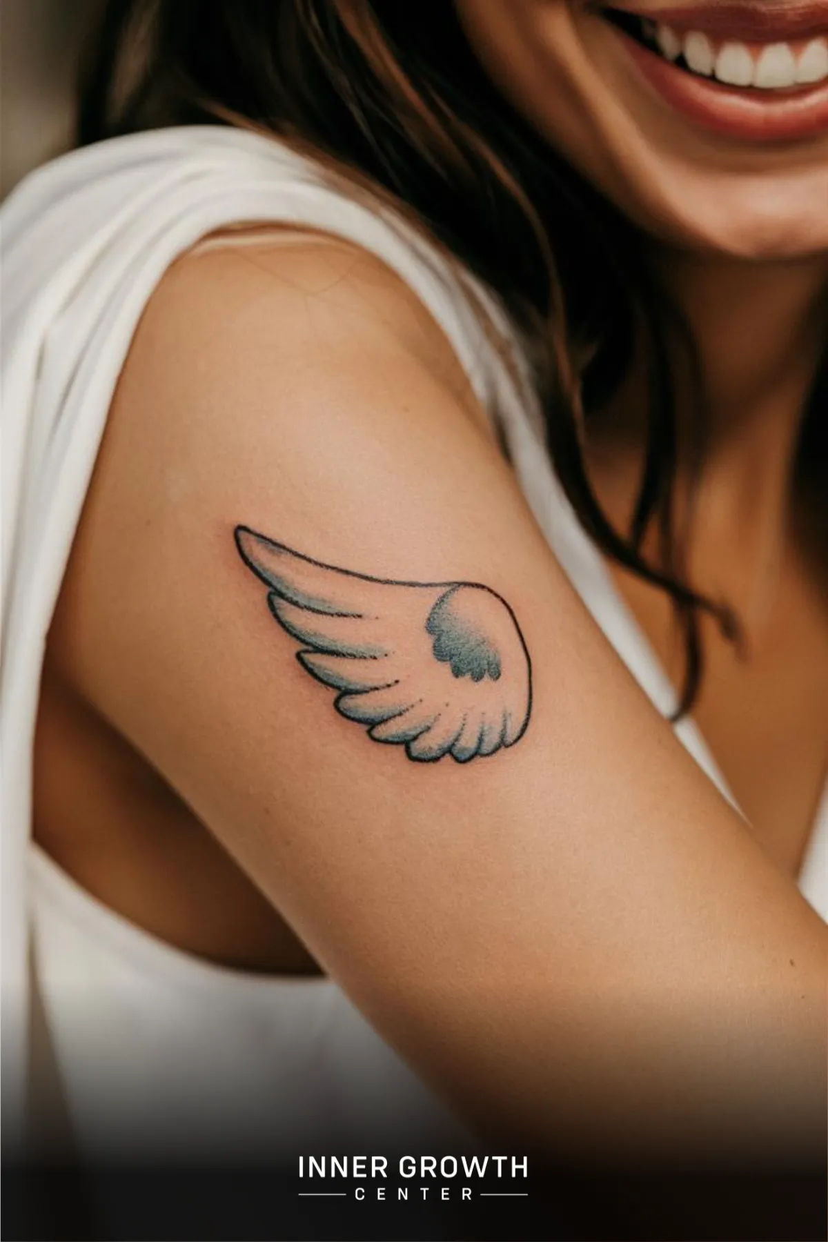 A woman with an angel wing tattoo on her arm.