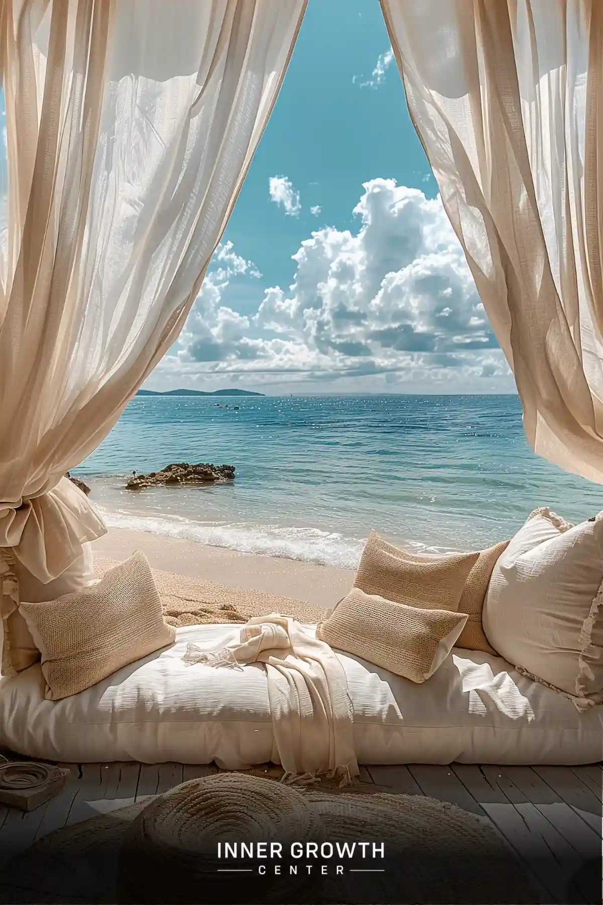 A cozy daybed with pillows framed by flowing curtains overlooking a serene beach and ocean view.