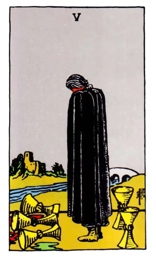 A figure in a long dark cloak, stands facing away, looking down at spilt cups as the 5 of Cups tarot card.