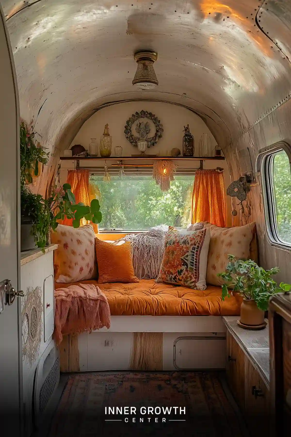 A cozy Airstream interior transformed into a bohemian meditation space with orange cushions and plants.